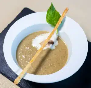 Bol de velouté de champignons onctueux garni de persil et croûtons, sur une table cosy d'automne