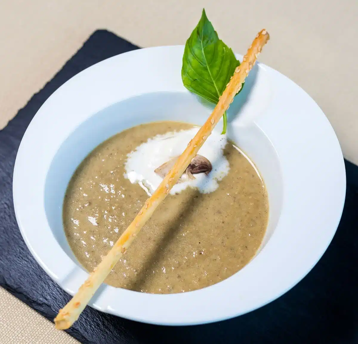 Bol de velouté de champignons onctueux garni de persil et croûtons, sur une table cosy d'automne
