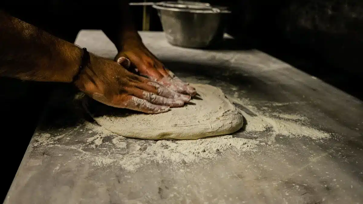 Mains pétrissant une pâte lisse et élastique sur une surface farinée