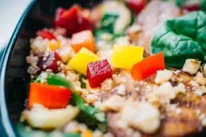 Bol de salade colorée avec chou-fleur, quinoa et légumes rôtis sur une table en bois