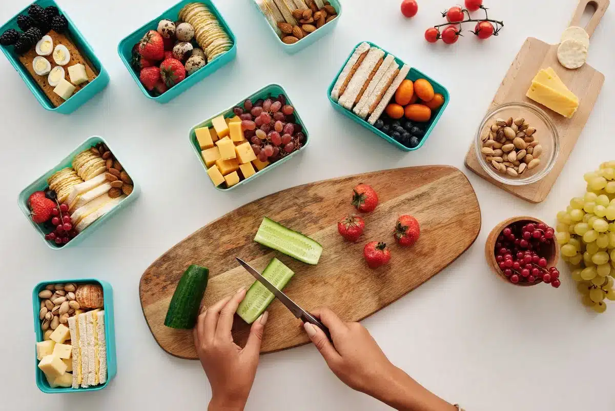 Lunchbox équilibrée avec compartiments contenant lentilles, patate douce rôtie, poulet et légumes frais