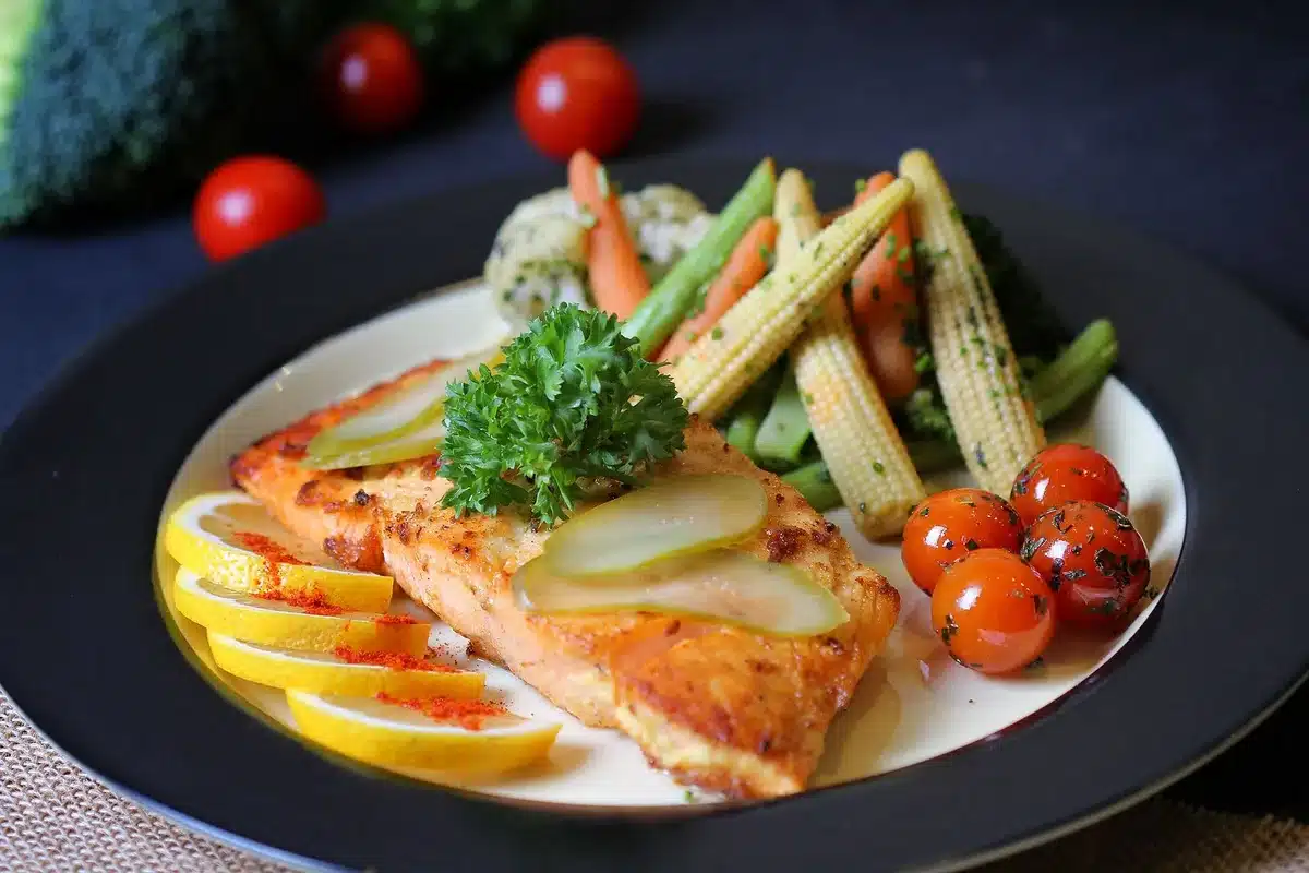Assiette équilibrée avec protéines, légumes et féculents complets sur une table ensoleillée