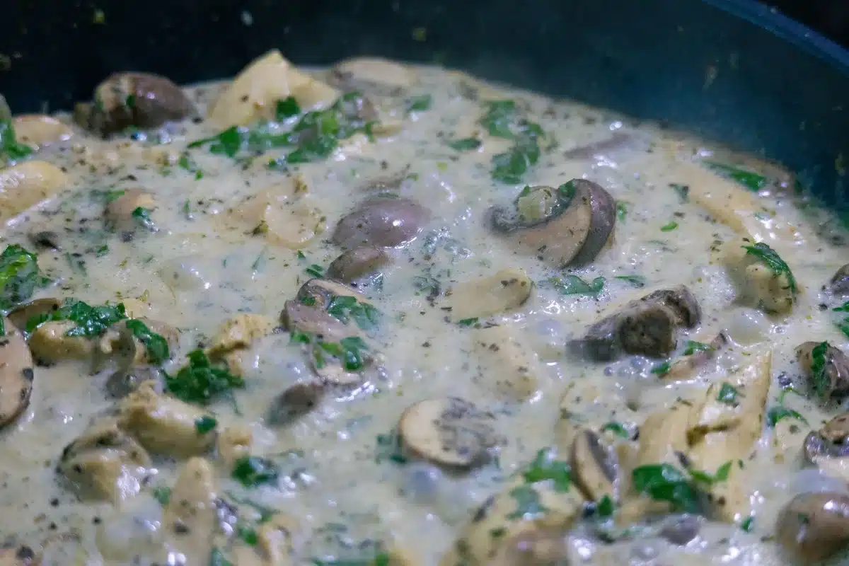 Préparation de la sauce Thermidor dans une casserole avec échalotes, vin blanc et crème