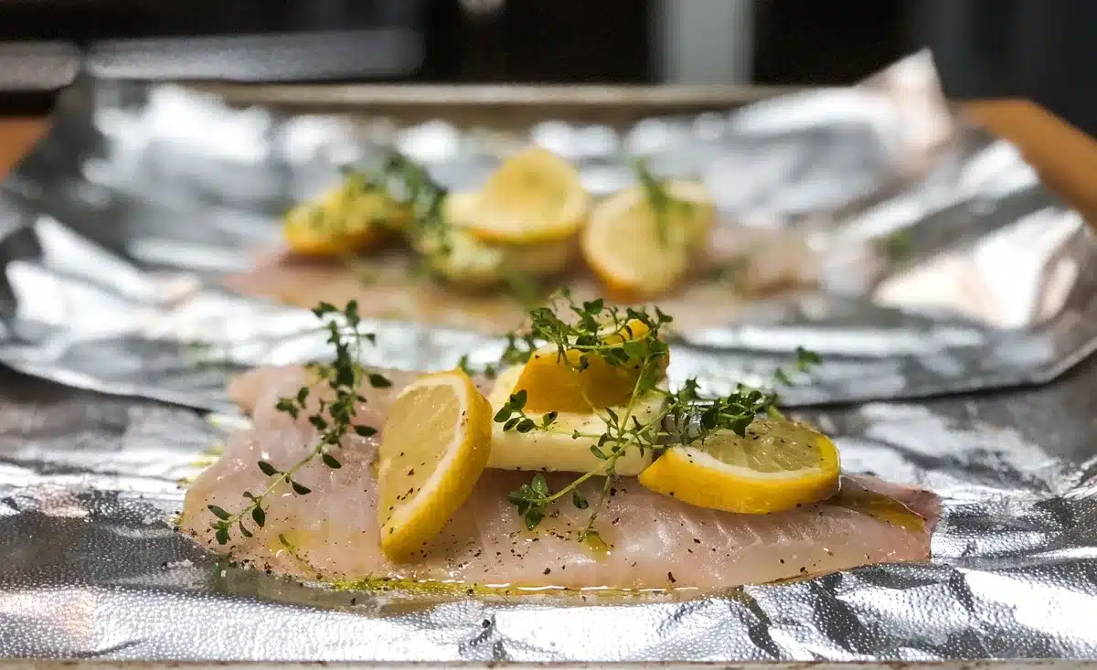 Pavé de saumon frais avec rondelles de citron et herbes sur papier aluminium