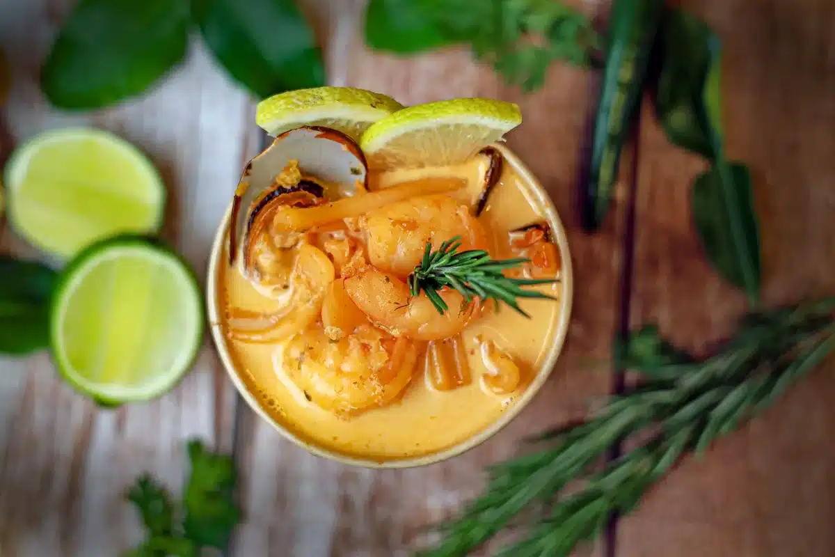 Bol de surimi au lait de coco et tomates fumant sous une lumière tropicale chaleureuse