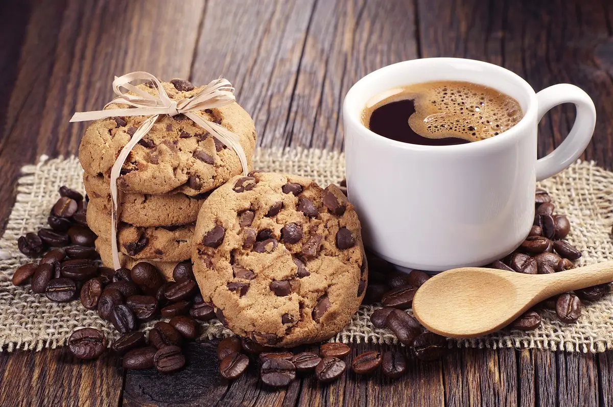 Cuillère déposant des tas de pâte à biscuits sans cuisson sur du papier parchemin