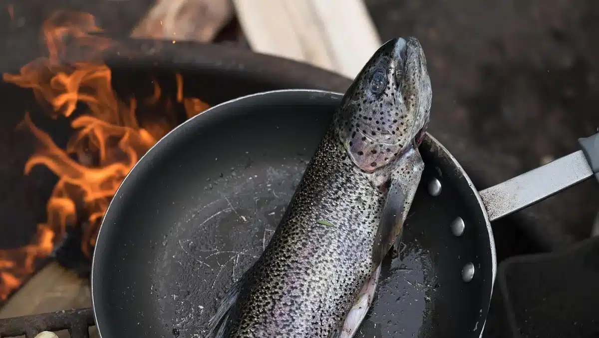 Petits poissons en train de frire dans une poêle avec huile chaude