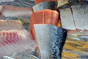 Plan de travail en cuisine en plein jour, filets de poisson farinés et gousse de vanille ouverte