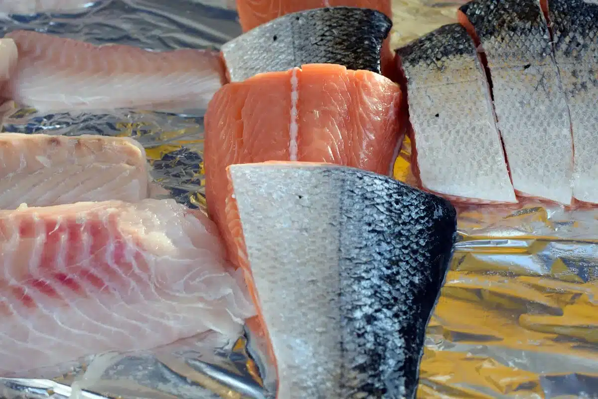 Plan de travail en cuisine en plein jour, filets de poisson farinés et gousse de vanille ouverte