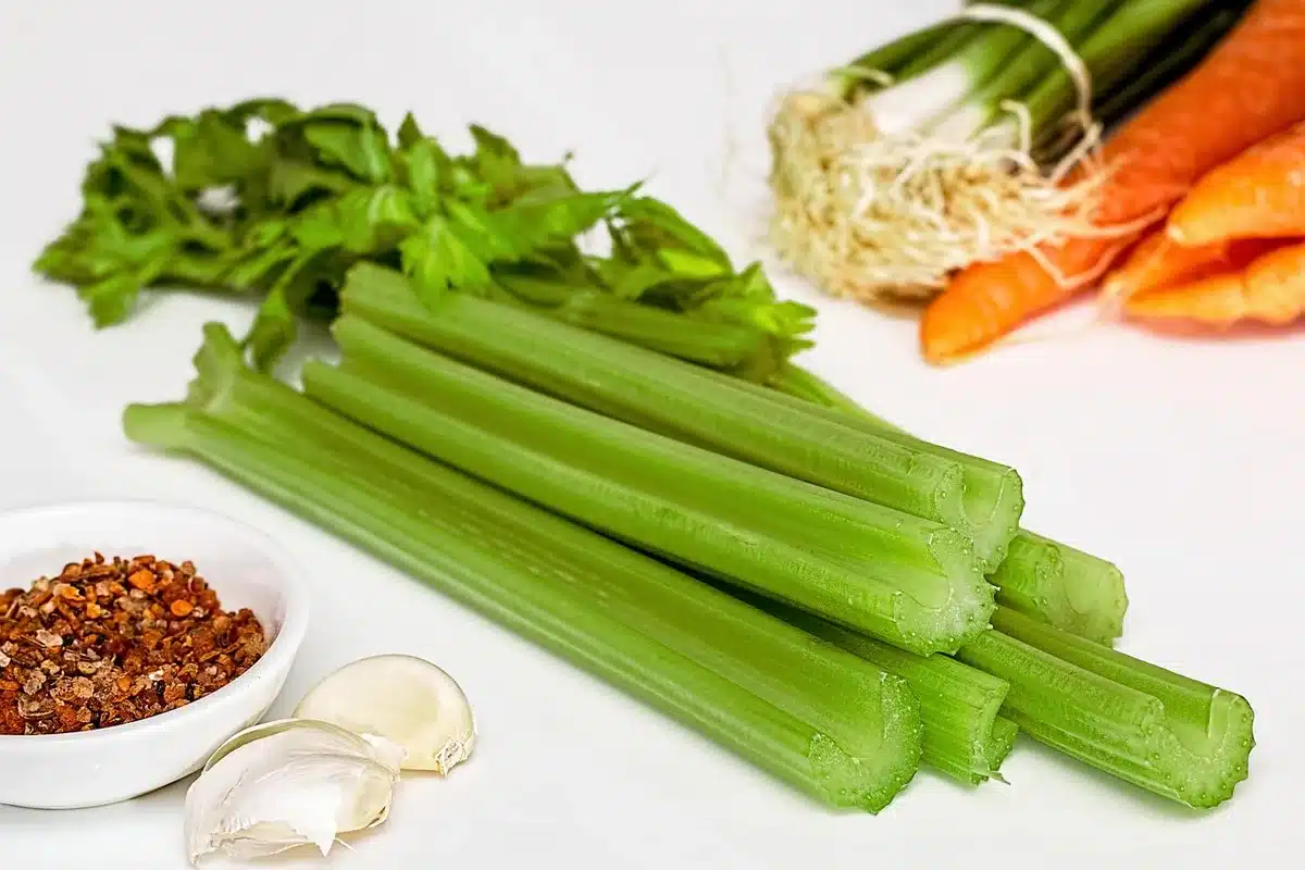 Wok fumant dans une cuisine lumineuse avec légumes colorés et bol de nouilles jaunes