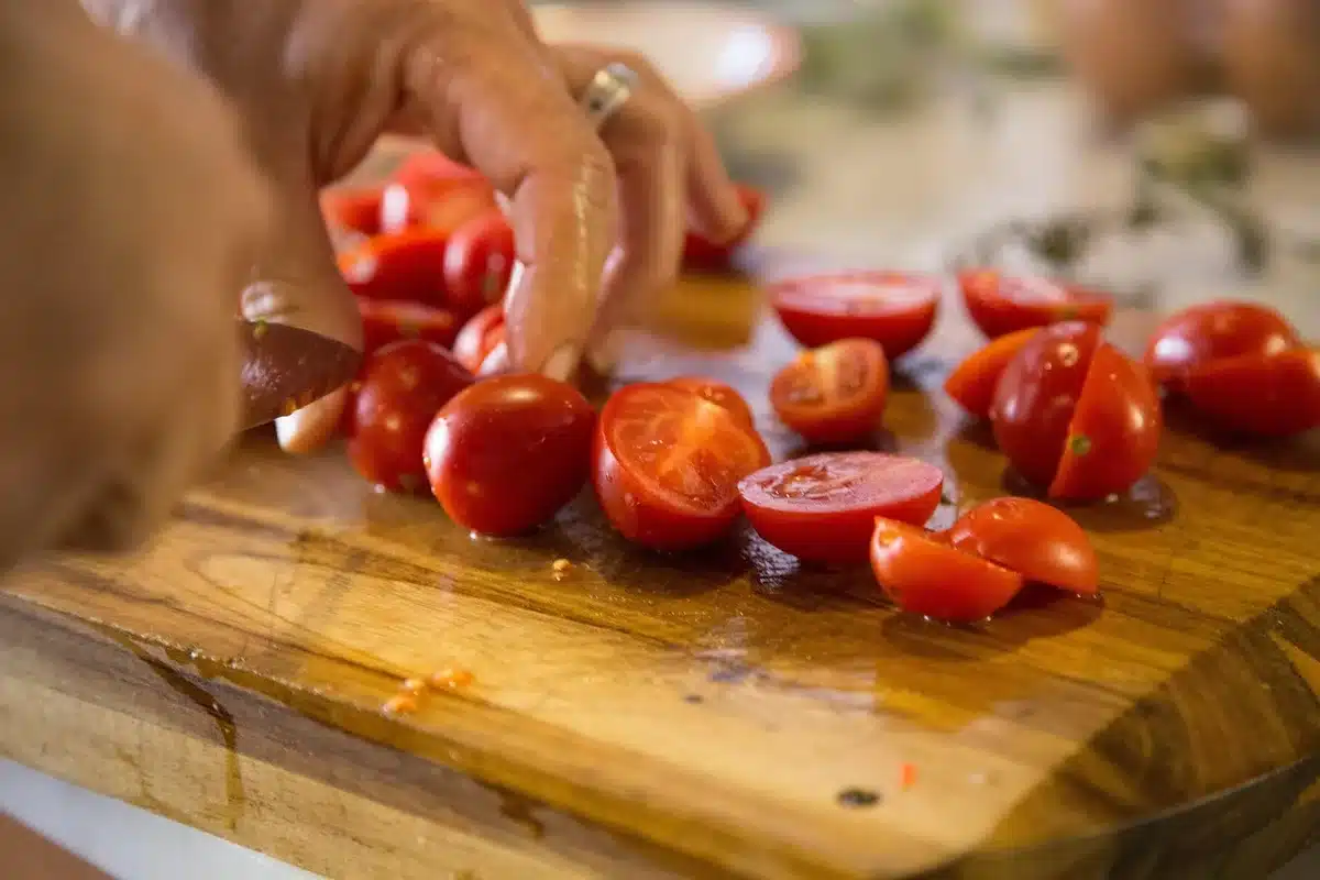 Personne anonyme coupant des carottes et un poivron sur une planche à découper en journée